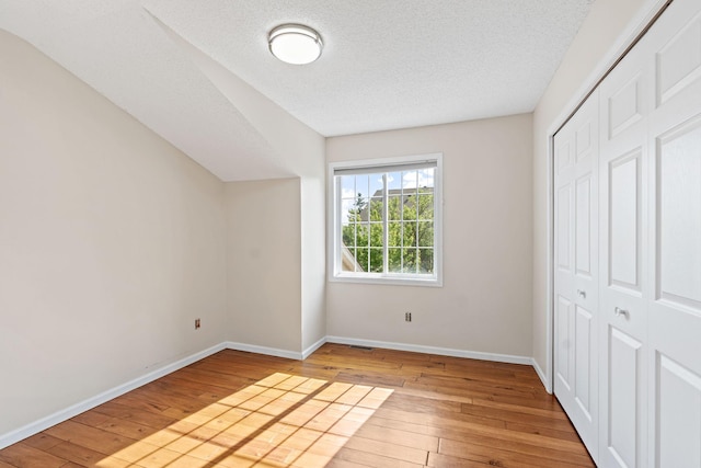 7719 Nicholas Way, Chanhassen, MN 55317 - unfurnished bedroom with hardwood / wood-style floors, baseboards, a closet, and a textured ceiling