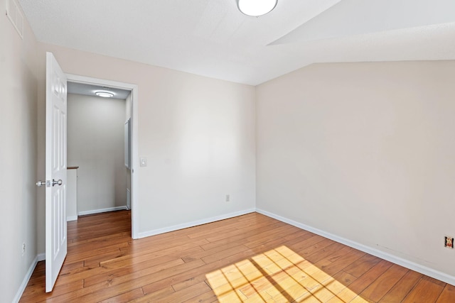 7719 Nicholas Way, Chanhassen, MN 55317 - empty room featuring light wood finished floors, vaulted ceiling, and baseboards
