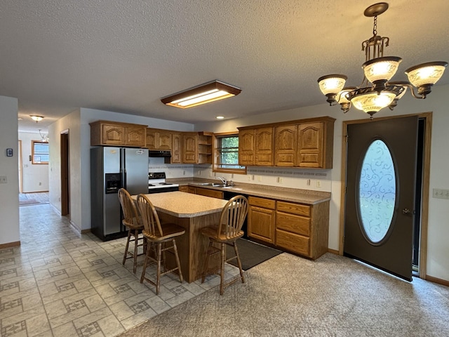 23759 Clarissa Haven Dr, Girard Twp, MN 56551 - kitchen with stainless steel fridge, electric stove, a sink, brown cabinets, and open shelves