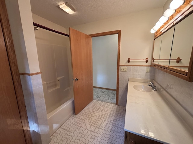 23759 Clarissa Haven Dr, Girard Twp, MN 56551 - bathroom with vanity, tile walls, a wainscoted wall, a textured ceiling, and shower / bath combination