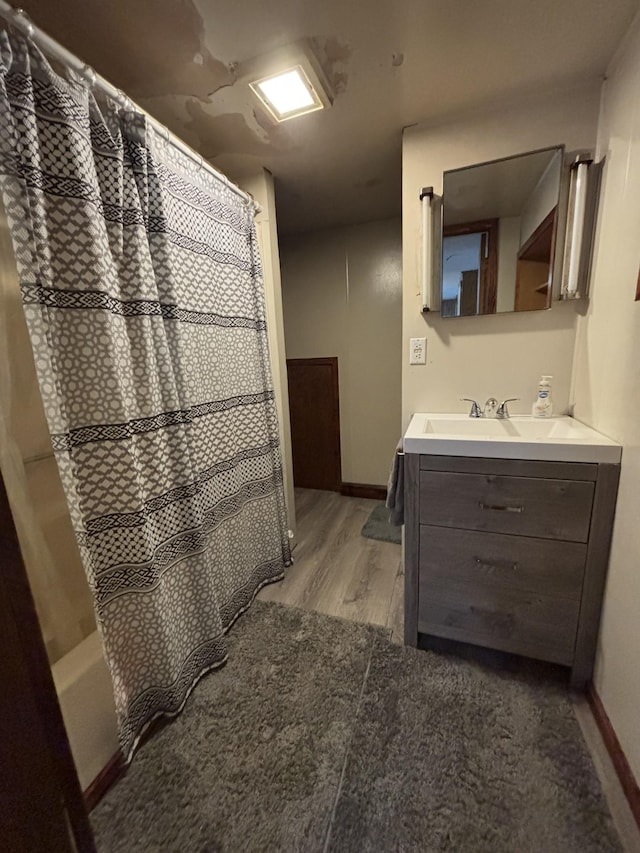 23759 Clarissa Haven Dr, Girard Twp, MN 56551 - bathroom featuring vanity, wood finished floors, shower / bath combo with shower curtain, and baseboards