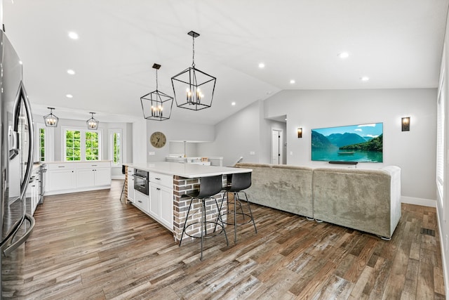 1600 Buffalo Cv, Buffalo, MN 55313 - kitchen with stainless steel fridge, open floor plan, white cabinetry, wood finished floors, and lofted ceiling