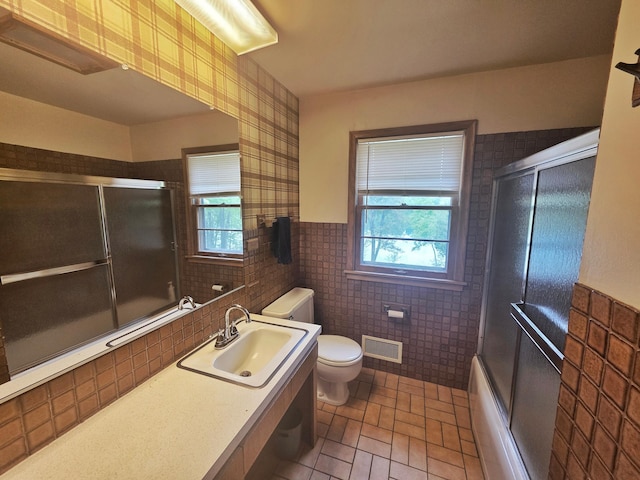1331 9th St, Grand Rapids, MN 55744 - bathroom with plenty of natural light, toilet, tile walls, vanity, and wainscoting