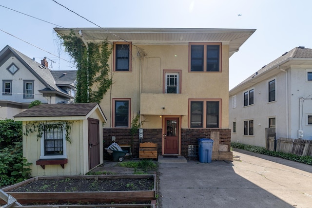 1808 Taylor St NE, Minneapolis, MN 55418 - view of front facade with a storage unit, a vegetable garden, brick siding, and stucco siding