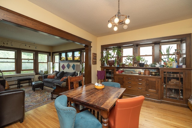 1808 Taylor St NE, Minneapolis, MN 55418 - dining area with light wood-type flooring, healthy amount of natural light, a chandelier, and a textured ceiling