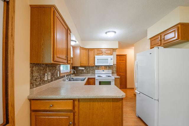 601 4th Ave N, Sauk Rapids, MN 56379 - kitchen with white appliances, light wood-style flooring, backsplash, a peninsula, and light countertops