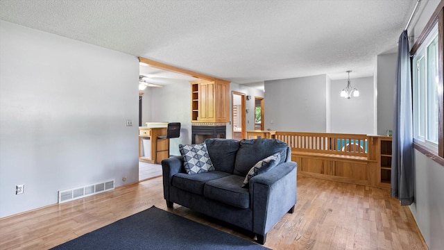 1504 89th Ave N, Brooklyn Park, MN 55444 - living area featuring light wood finished floors, a textured ceiling, a chandelier, and ceiling fan