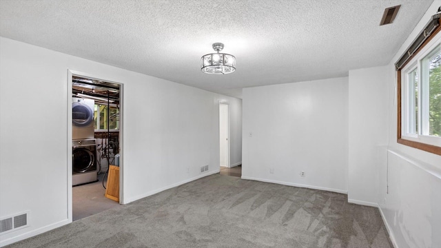 1504 89th Ave N, Brooklyn Park, MN 55444 - carpeted spare room with stacked washer and clothes dryer, a textured ceiling, and baseboards