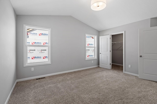 1020 2nd St NW, Delano, MN 55328 - unfurnished bedroom with vaulted ceiling, carpet, a walk in closet, and baseboards
