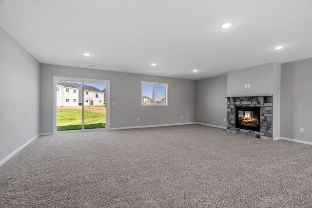 1020 2nd St NW, Delano, MN 55328 - unfurnished living room with carpet flooring, recessed lighting, a stone fireplace, and baseboards