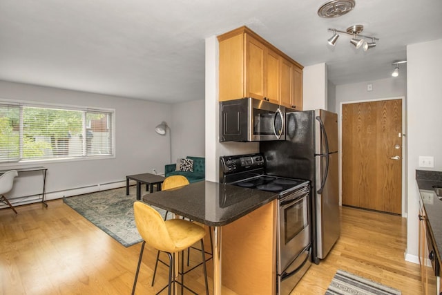3018 Aldrich Ave S Unit 12, Minneapolis, MN 55408 - kitchen featuring stainless steel appliances, light wood-style floors, a breakfast bar area, and baseboard heating