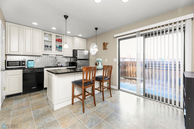 309 12 1/2 Ave E, West Fargo, ND 58078 - kitchen with stainless steel appliances, dark countertops, a breakfast bar area, backsplash, and glass insert cabinets