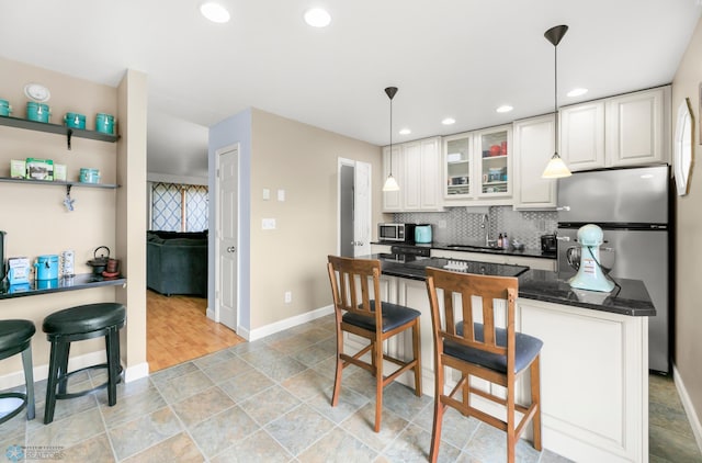 309 12 1/2 Ave E, West Fargo, ND 58078 - kitchen with stainless steel appliances, baseboards, a breakfast bar, backsplash, and white cabinetry