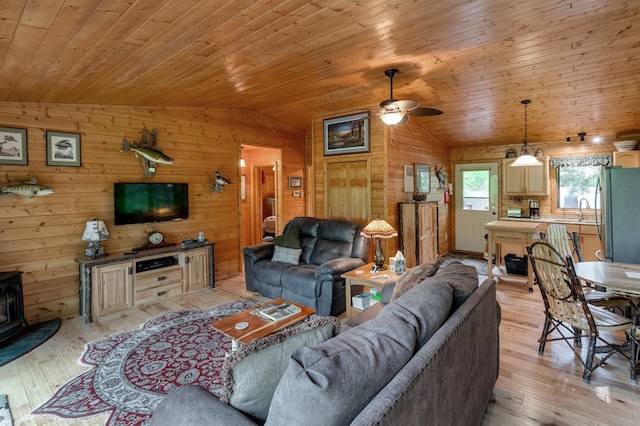 40456 Little Pine River Rd, Emily, MN 56447 - living area with vaulted ceiling, a wood stove, light wood finished floors, wood walls, and wooden ceiling