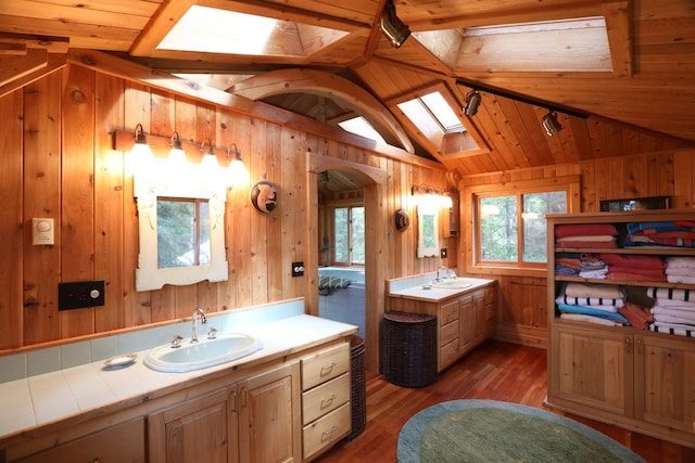 X Waters Island, Morse Twp, MN 55731 - bathroom featuring a skylight, vaulted ceiling, two vanities, wooden walls, and wood finished floors