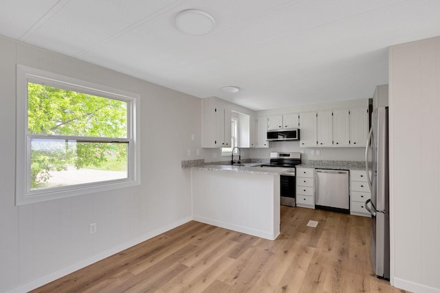 19363 County Road 21, Eden Lake Twp, MN 56368 - kitchen featuring stainless steel appliances, light wood-style flooring, a peninsula, baseboards, and white cabinets