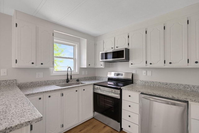 19363 County Road 21, Eden Lake Twp, MN 56368 - kitchen featuring stainless steel appliances, a sink, light wood-style flooring, and white cabinets