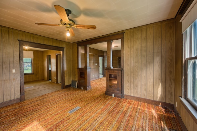 411 6th St, Bird Island, MN 55310 - carpeted empty room featuring wooden walls, a ceiling fan, and ornate columns