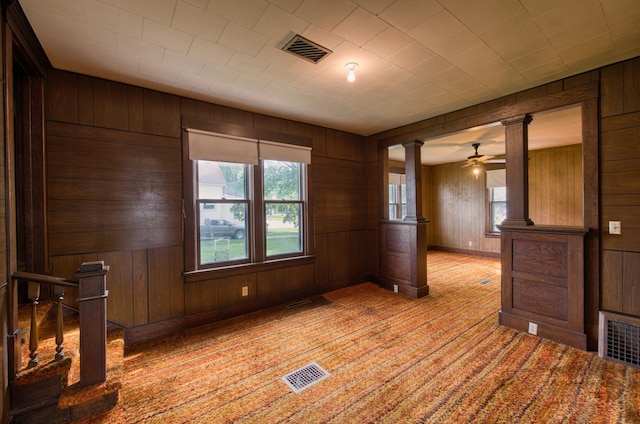411 6th St, Bird Island, MN 55310 - unfurnished room with ornate columns, wood walls, light colored carpet, ceiling fan, and baseboards