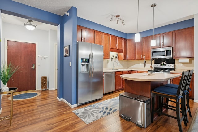 3800 85th Ave N Unit 312, Brooklyn Park, MN 55443 - kitchen with appliances with stainless steel finishes, light countertops, wood finished floors, a sink, and pendant lighting