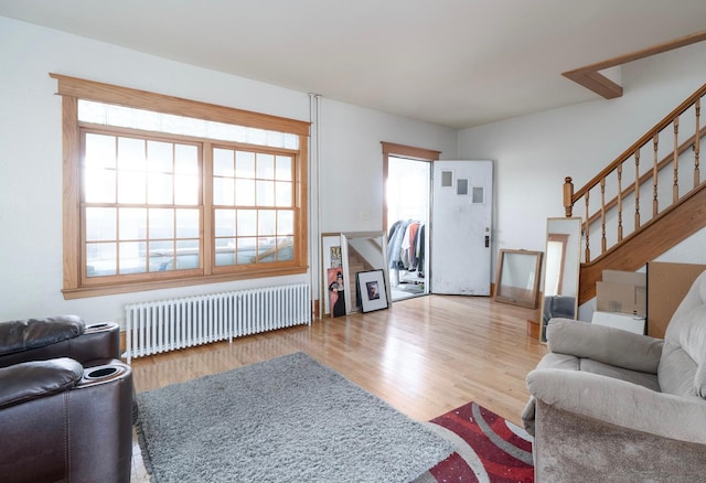 1638 Concordia Ave, Saint Paul, MN 55104 - living area with radiator, healthy amount of natural light, wood finished floors, and stairway