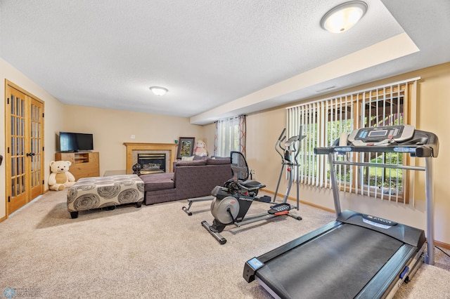3138 25th Ave S, Fargo, ND 58103 - workout area featuring carpet, a textured ceiling, a glass covered fireplace, and baseboards