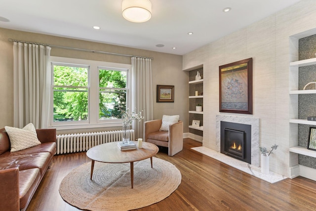 1617 Franklin Ave, Minneapolis, MN 55405 - living room featuring radiator, built in shelves, wood finished floors, a premium fireplace, and recessed lighting
