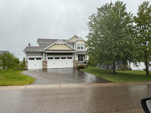 11543 Harbor Ln, Woodbury, MN 55129 - view of front of home featuring driveway, a front lawn, an attached garage, and stone siding