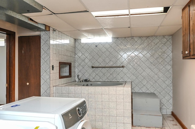 2904 Silver Lake Ct NE, Saint Anthony, MN 55421 - full bathroom featuring washer / clothes dryer, tile walls, a relaxing tiled tub, a drop ceiling, and tile patterned floors
