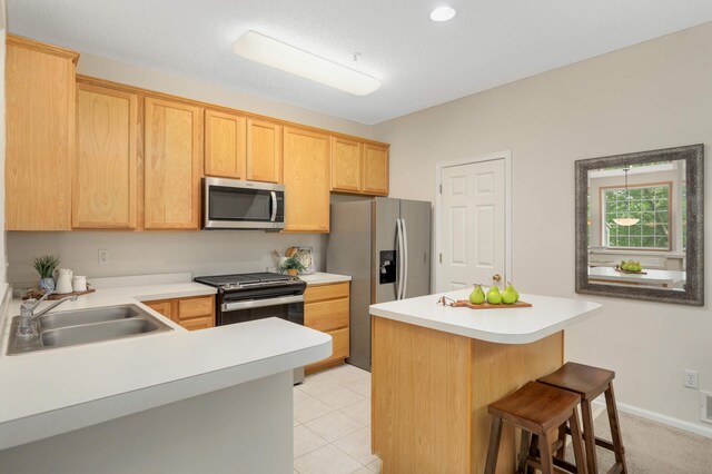 13872 52nd Ave N, Plymouth, MN 55446 - kitchen with stainless steel appliances, a sink, a kitchen bar, light countertops, and light brown cabinets