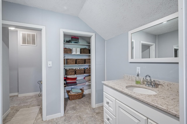 12801 40th St NE, Saint Michael, MN 55376 - bathroom featuring a textured ceiling, vanity, vaulted ceiling, and baseboards