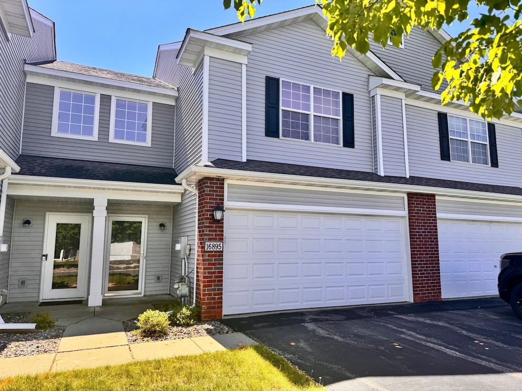 16895 78th Pl N, Maple Grove, MN 55311 - view of front facade featuring an attached garage, brick siding, and driveway