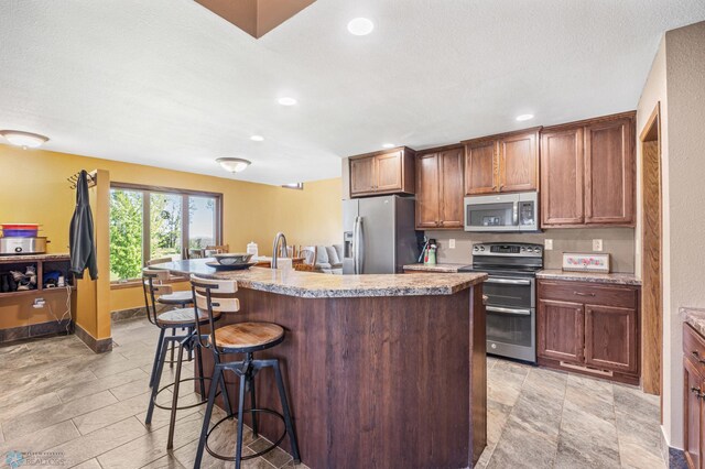 6056 170th Ave SE, Walcott, ND 58077 - kitchen featuring appliances with stainless steel finishes, a breakfast bar, an island with sink, recessed lighting, and baseboards