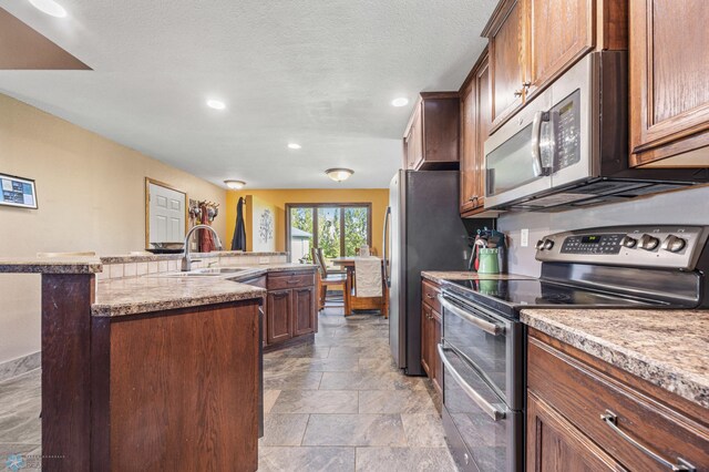 6056 170th Ave SE, Walcott, ND 58077 - kitchen with appliances with stainless steel finishes, a sink, stone finish floors, recessed lighting, and an island with sink