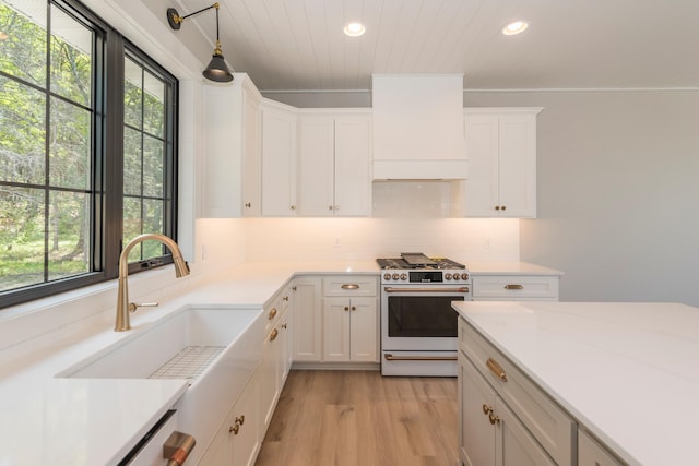 29655 E Horseshoe Lake Rd, Mission Twp, MN 56465 - kitchen featuring gas range oven, premium range hood, white cabinetry, light wood-type flooring, and light countertops