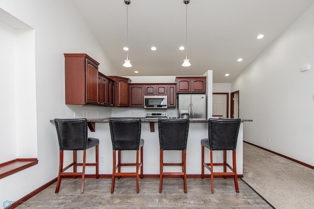 828 Cinnamon Ridge Pl, West Fargo, ND 58078 - kitchen featuring appliances with stainless steel finishes, lofted ceiling, a peninsula, a kitchen bar, and hanging light fixtures