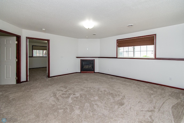 828 Cinnamon Ridge Pl, West Fargo, ND 58078 - unfurnished living room with carpet floors, a glass covered fireplace, a textured ceiling, and baseboards