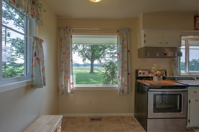 2509 Jade St, Mora, MN 55051 - kitchen with stainless steel electric range oven, range hood, white cabinetry, and light tile patterned flooring