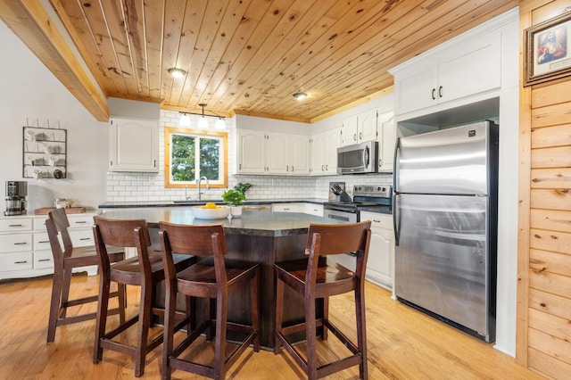 2487 2nd St SW, Buffalo, MN 55313 - kitchen with stainless steel appliances, wood ceiling, light wood-type flooring, dark countertops, and white cabinets