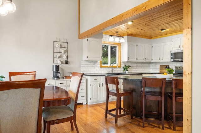 2487 2nd St SW, Buffalo, MN 55313 - kitchen featuring stainless steel appliances, a kitchen breakfast bar, light wood-type flooring, white cabinetry, and wooden ceiling