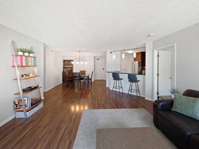 401 1st St Unit 601, Minneapolis, MN 55401 - living area featuring dark wood-style floors, a textured ceiling, track lighting, baseboards, and a chandelier