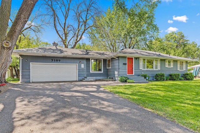 7109 Douglas Dr N, Brooklyn Park, MN 55429 - view of front facade featuring a garage, asphalt driveway, a front yard, and a chimney