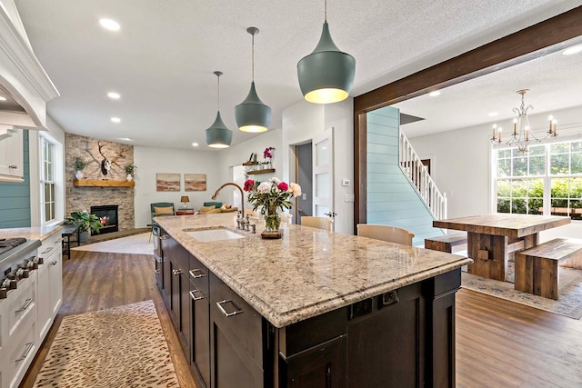 15084 Appaloosa Trl NE, Prior Lake, MN 55372 - kitchen featuring a sink, dark wood-style floors, a fireplace, recessed lighting, and light stone counters