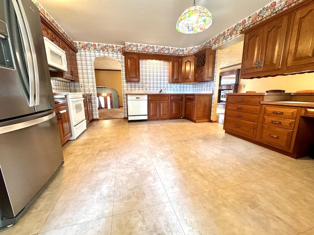 212 Carrow Cir, Marshall, MN 56258 - kitchen featuring white appliances, arched walkways, decorative backsplash, brown cabinets, and light countertops