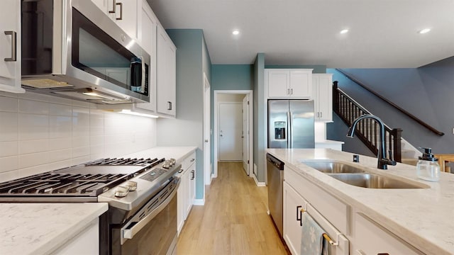 13323 Territorial Cir N, Maple Grove, MN 55369 - kitchen featuring stainless steel appliances, a sink, light wood-style floors, white cabinets, and tasteful backsplash