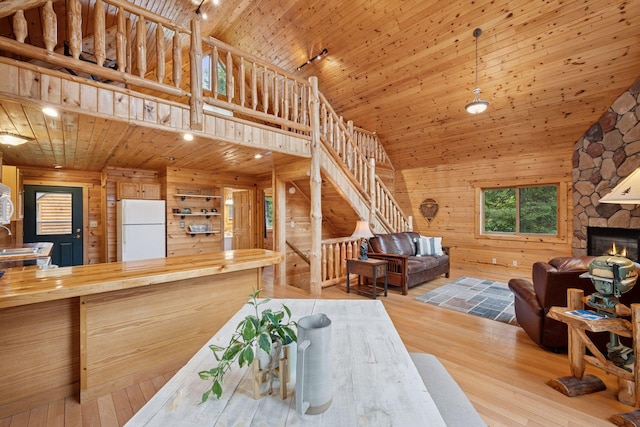 7194 Quentin Rd NE, Outing, MN 56662 - dining area featuring wood ceiling, wood walls, a fireplace, wood finished floors, and a high ceiling