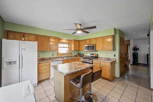 2651 Colfax Ave N, Minneapolis, MN 55411 - kitchen with stainless steel appliances, ceiling fan, a kitchen island, light tile patterned flooring, and a breakfast bar