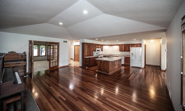 705 Grundhoefer Ct, Northfield, MN 55057 - kitchen with white appliances, lofted ceiling, a kitchen island, dark wood-style flooring, and light countertops