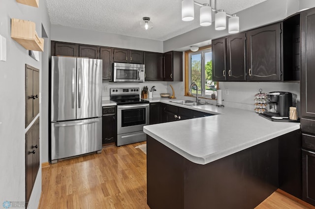3003 15th Ave S, Moorhead, MN 56560 - kitchen with stainless steel appliances, a sink, a textured ceiling, a peninsula, and light countertops