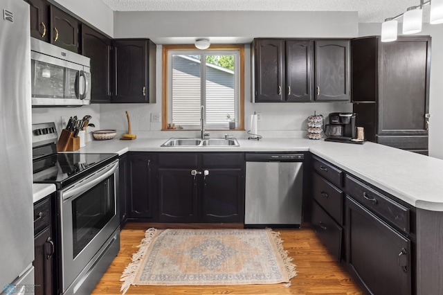 3003 15th Ave S, Moorhead, MN 56560 - kitchen featuring appliances with stainless steel finishes, a sink, a peninsula, light wood finished floors, and light countertops